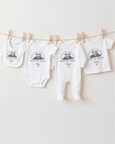A collection of baby clothes, including onesies and bibs, hanging on a clothesline.
