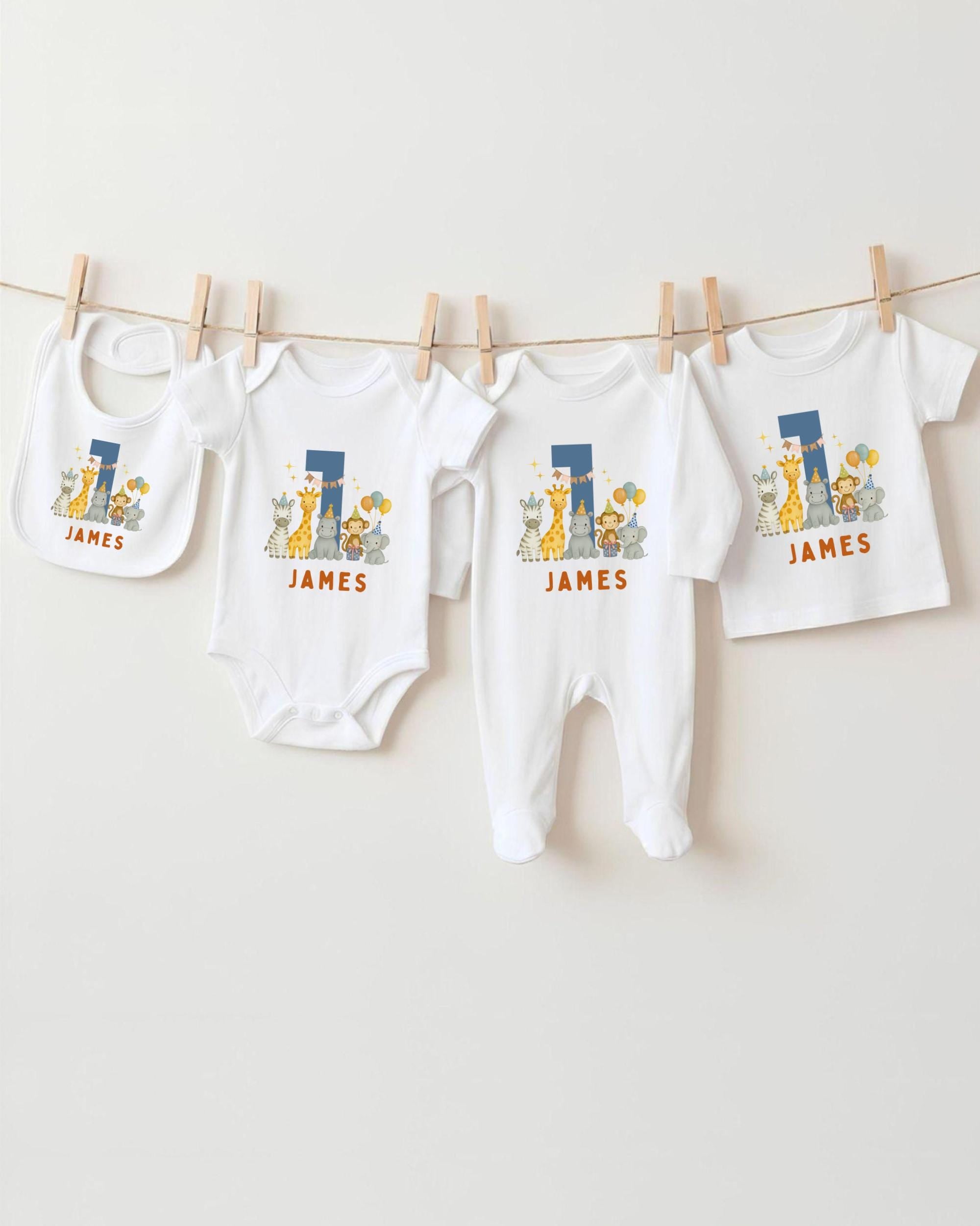 A collection of white baby clothes, including onesies and pants, with the name "James" printed on them, hanging on a clothesline.