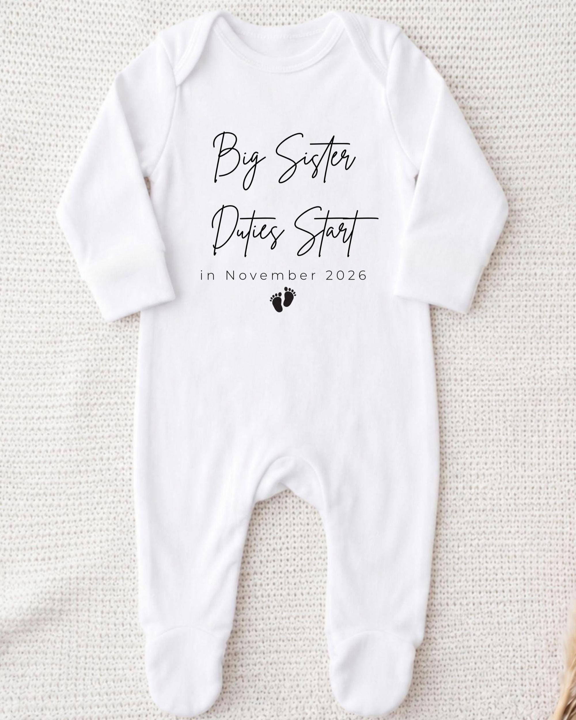 A white onesie with text printed on it, placed on a white background.
