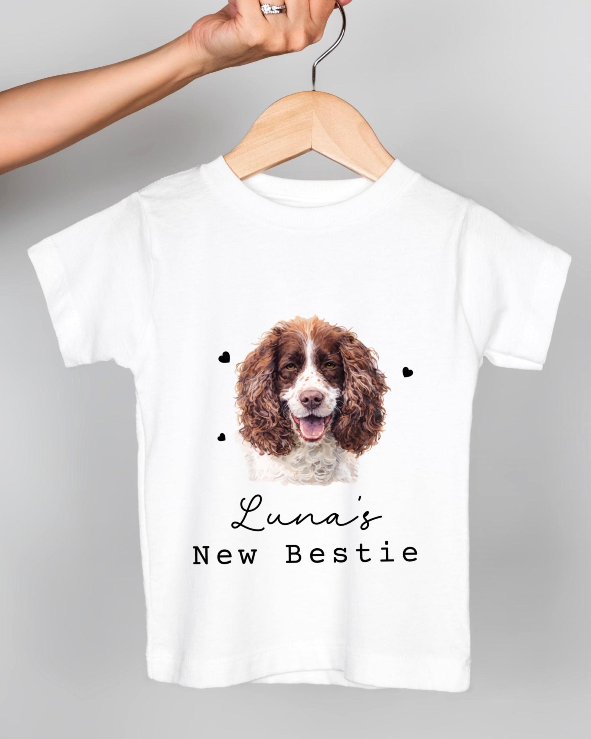 A white t-shirt with a picture of a brown and white dog, along with the text "Luna's New Bestie" printed on it.
