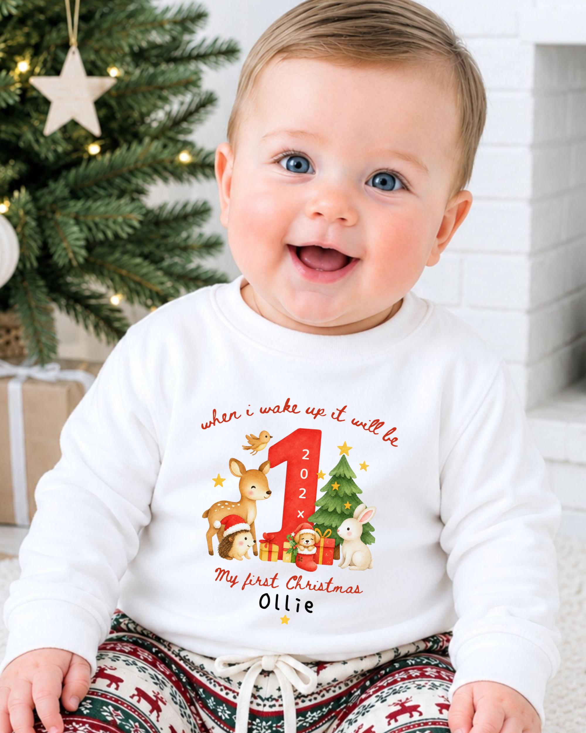 A smiling baby wearing a white onesie with a personalized design of a deer, rabbit, and Christmas tree.