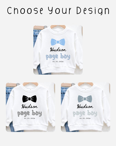 three white sweatshirts with the name "Hudson" and the date "01.01.2023" printed on them. The sweatshirts are arranged on hangers, suggesting they are for sale or display.
