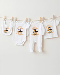 A collection of Halloween-themed baby clothes, including bibs and onesies, hanging on a clothesline.