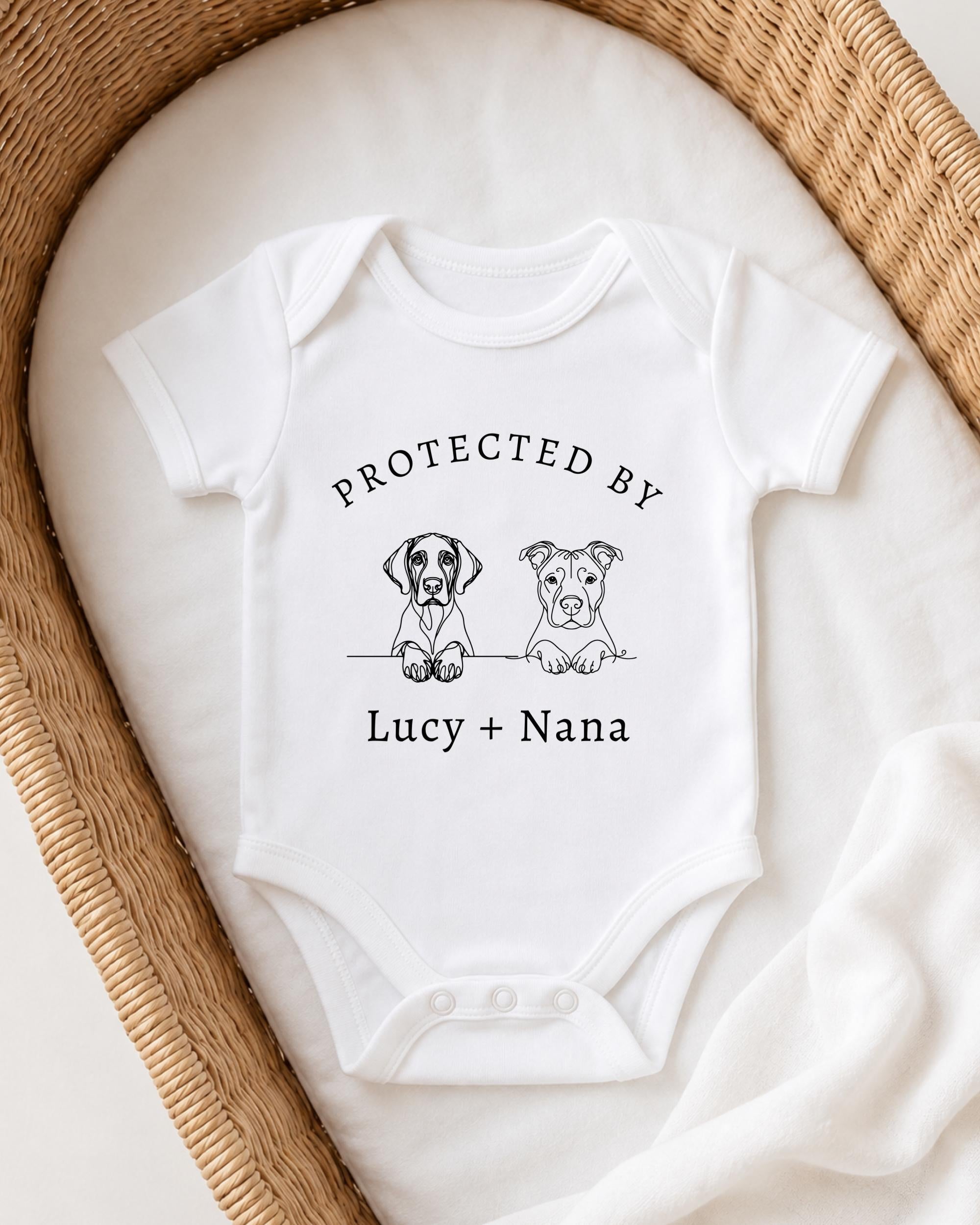 A white baby onesie with a graphic design of two dogs and the text "PROTECTED BY LUCY + NANA" printed on it.