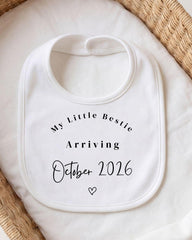 A white bib with text that reads "My Little Bestie Arriving October 2016" and a heart symbol.