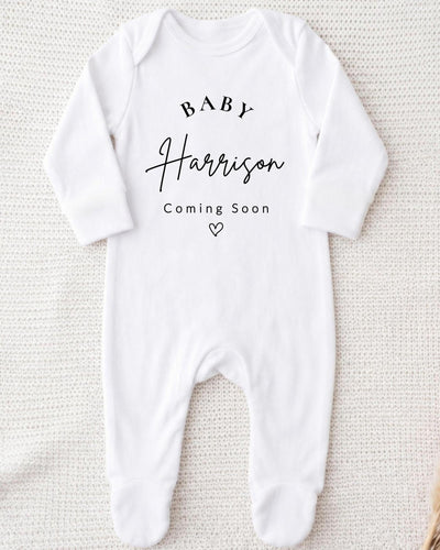 Personalised white Baby Vest with black 'Baby Harrison Coming Soon' lettering and an outline heart for a pregnancy announcement.