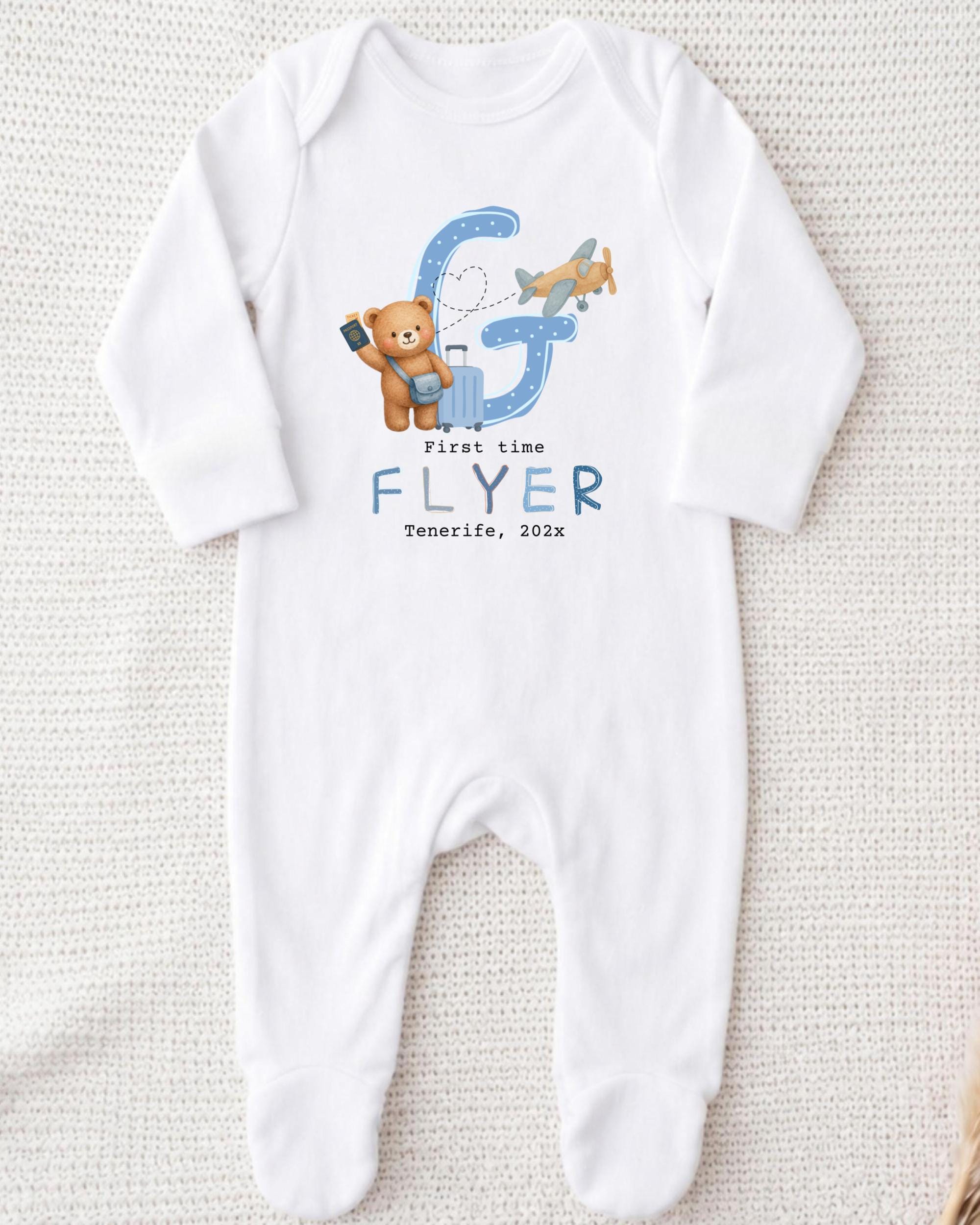 A white onesie with a graphic design featuring a teddy bear and an airplane.