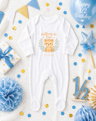 A baby onesie with a teddy bear design, surrounded by baby-themed decorations such as a balloon, confetti, and a star.