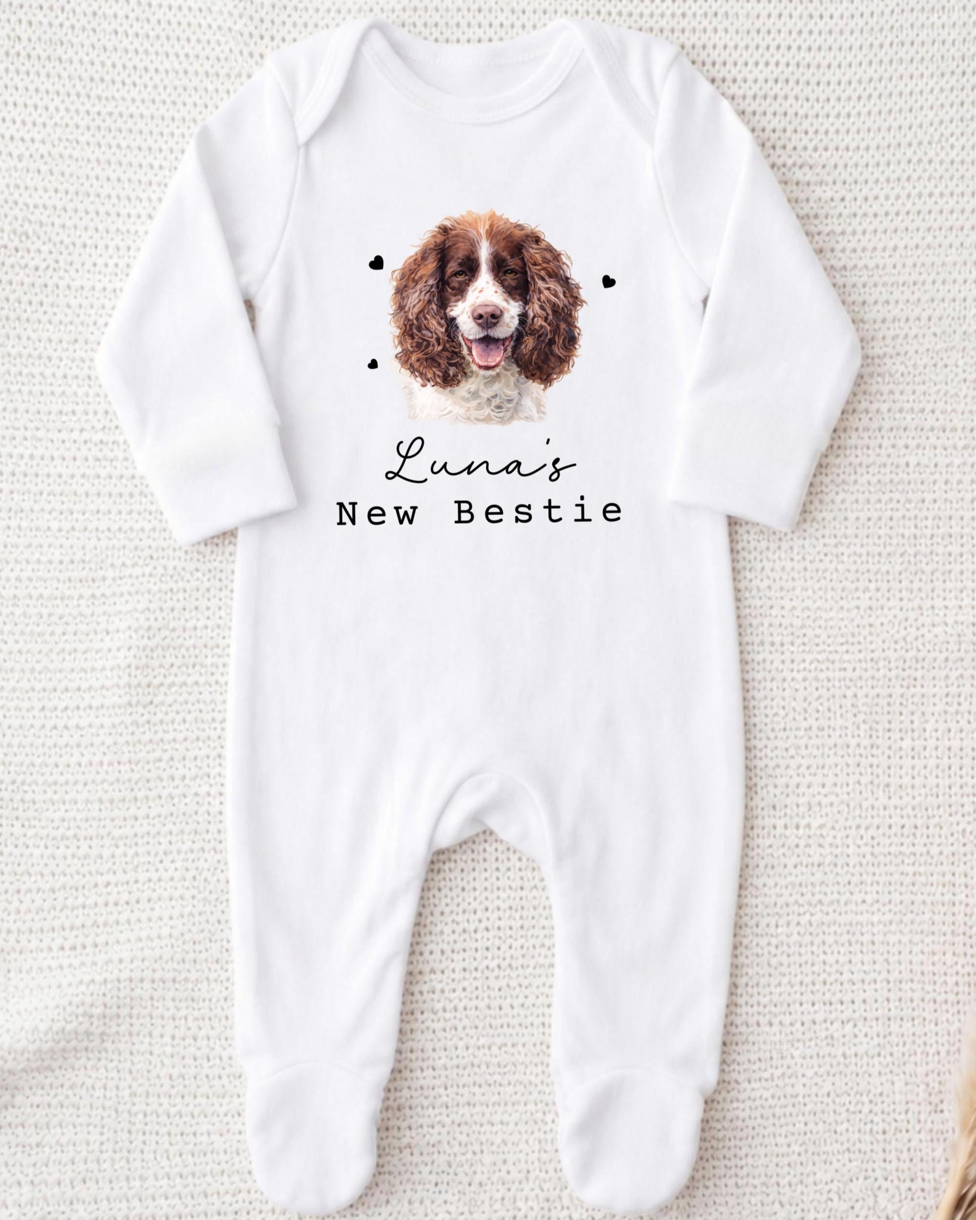 A white onesie with a picture of a brown and white dog on it, along with the text "Luna's New Bestie" printed on it.