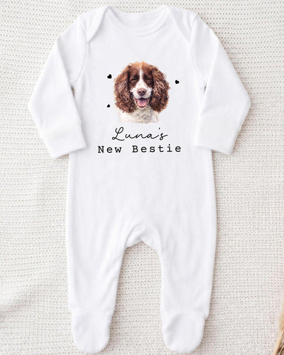 A white bodysuit with a picture of a brown and white dog on it, along with the text "Luna's New Bestie" printed on it.