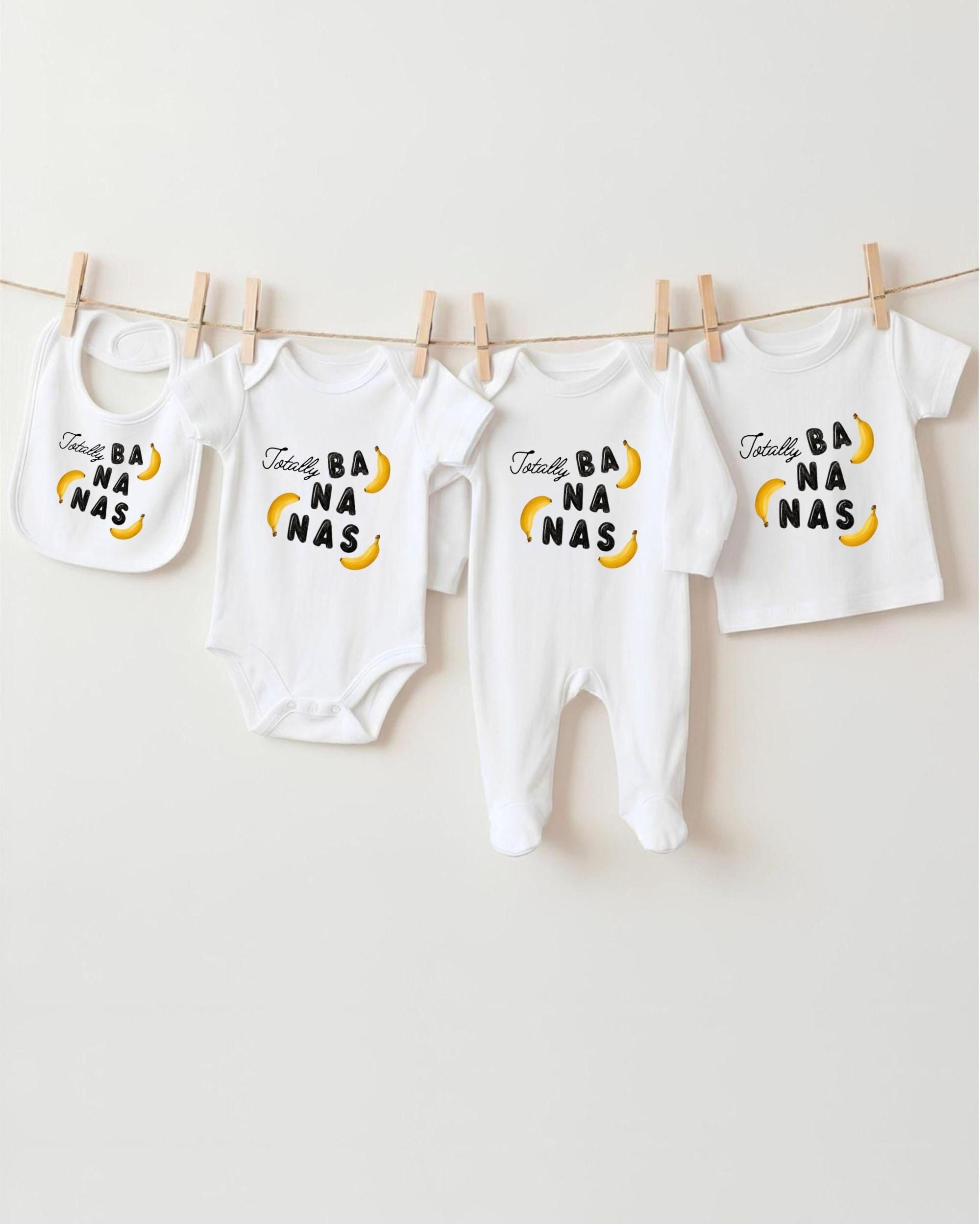 a collection of baby clothes, including onesies and bibs, hanging on a clothesline.