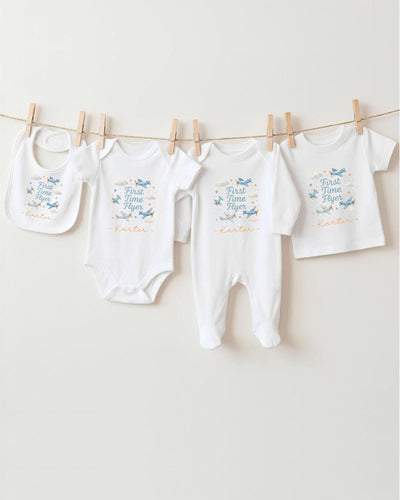 A row of four white baby clothes, including bibs and onesies, hanging on a clothesline.