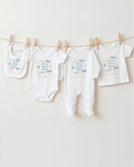 A row of four white baby clothes, including bibs and onesies, hanging on a clothesline.