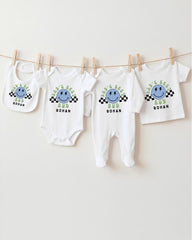 A collection of baby clothes, including onesies and bibs, hanging on a clothesline.