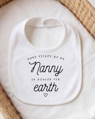 A white bib with black text that reads "Hand picked by my Nanny in Heaven for earth".