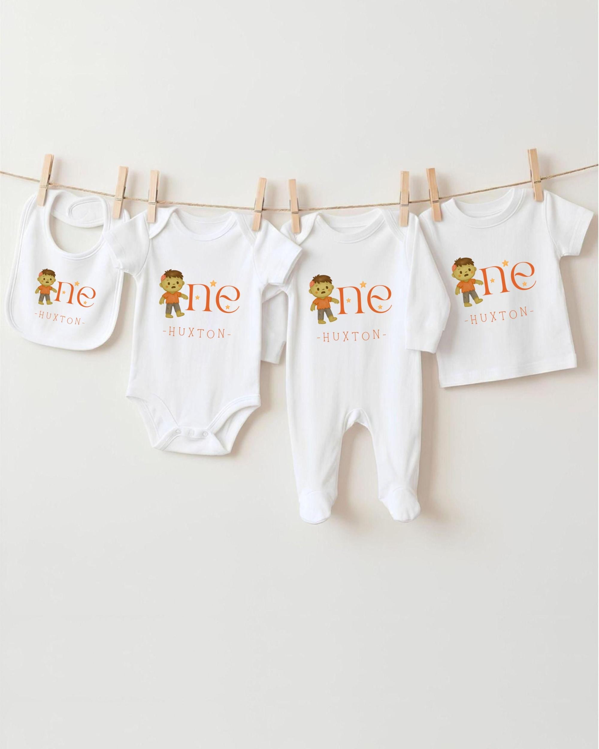 A collection of white baby clothes, including onesies and bibs, hanging on a clothesline.