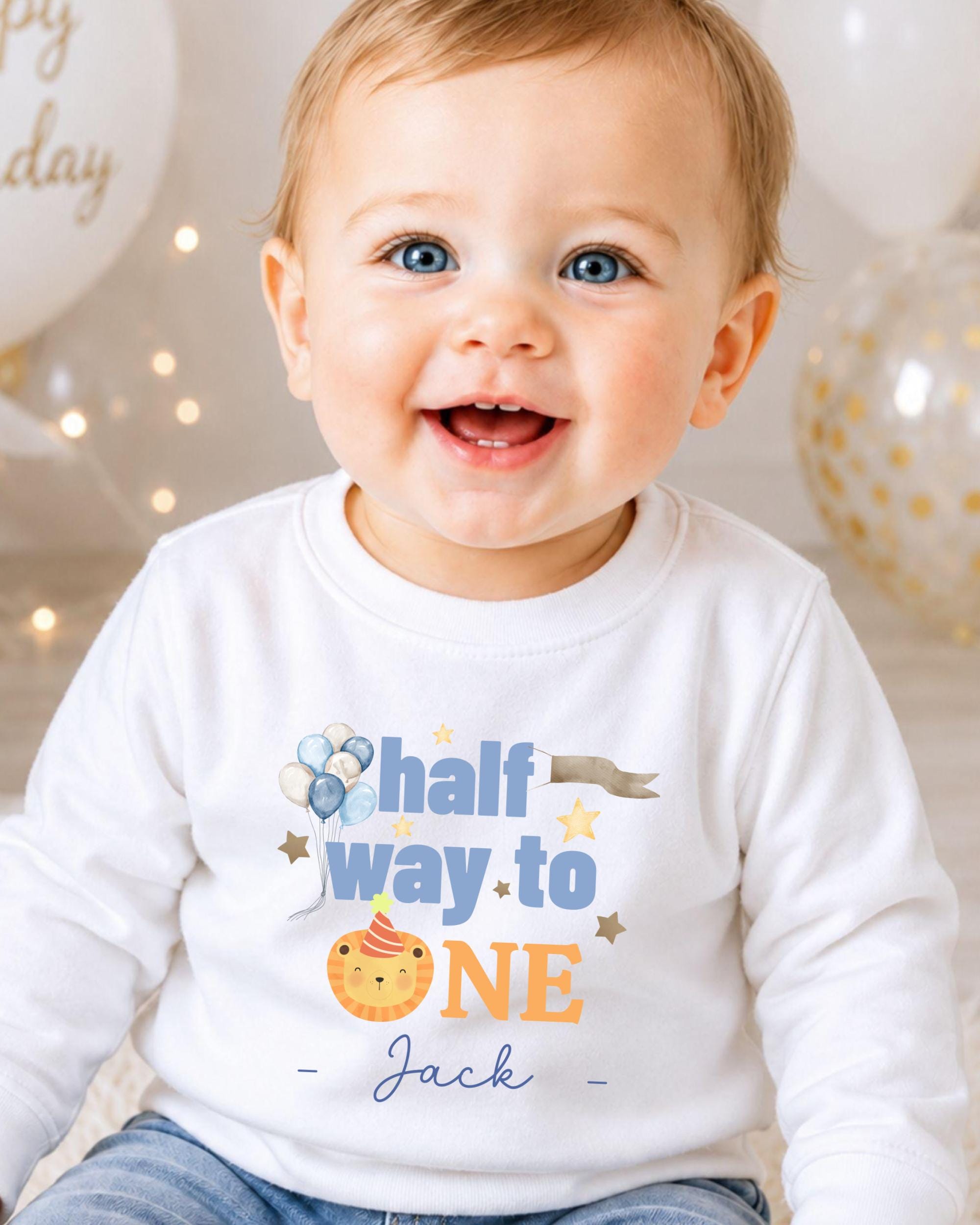 A smiling baby boy wearing a white shirt with a birthday message printed on it.
