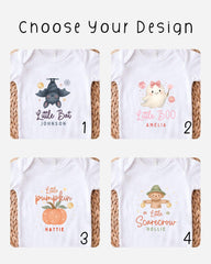 four different baby onesies with various designs, including a bat, a ghost, a pumpkin, and a scarecrow.