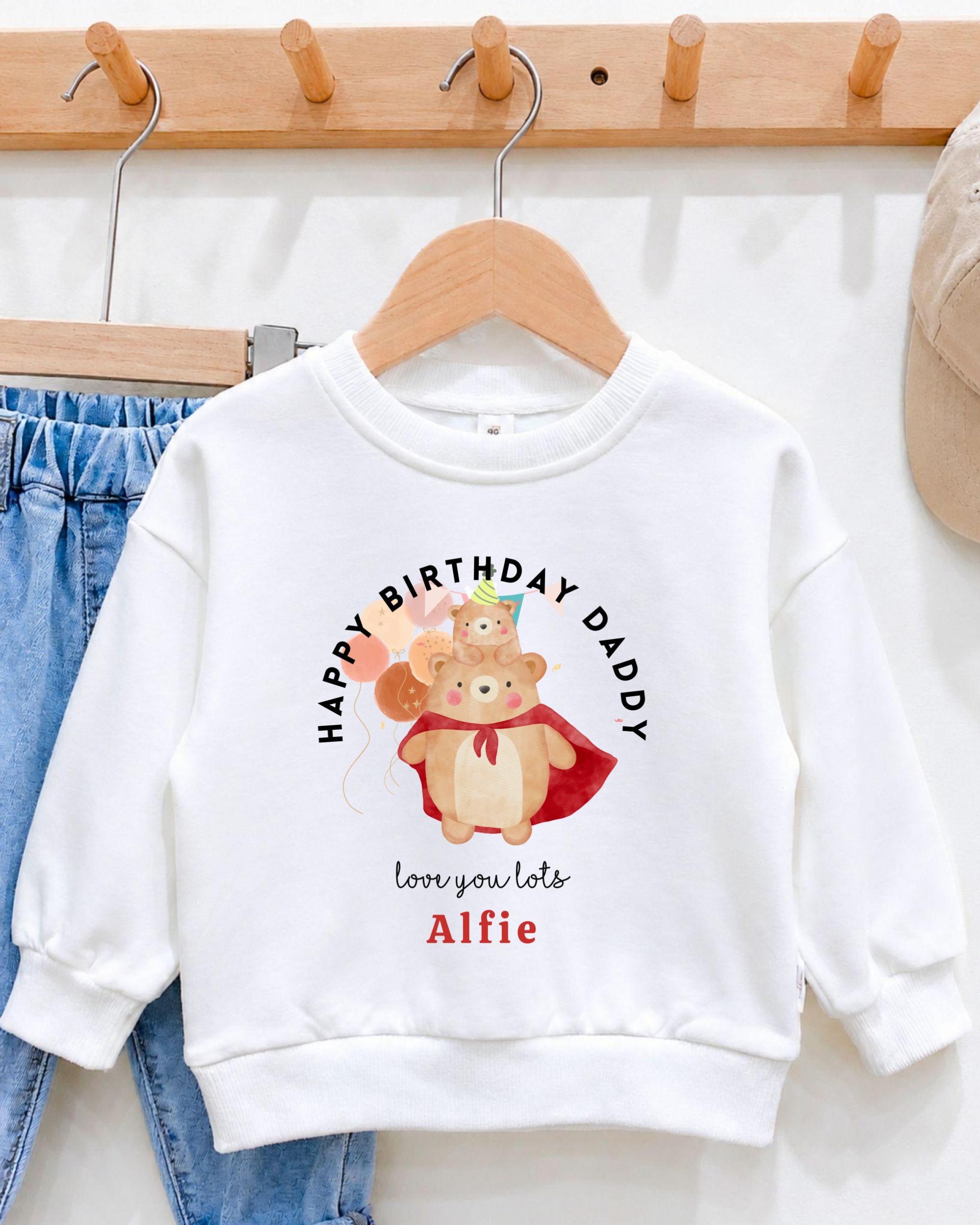 A white sweatshirt with a cartoon image of a bear wearing a superhero costume and the text "Happy Birthday Daddy" printed on it.