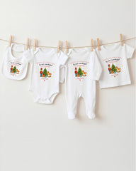 A collection of four white baby clothes, including onesies and pajamas, hanging on a clothesline.