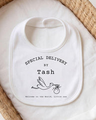 A white bib with text and a graphic design, placed on a white cloth.