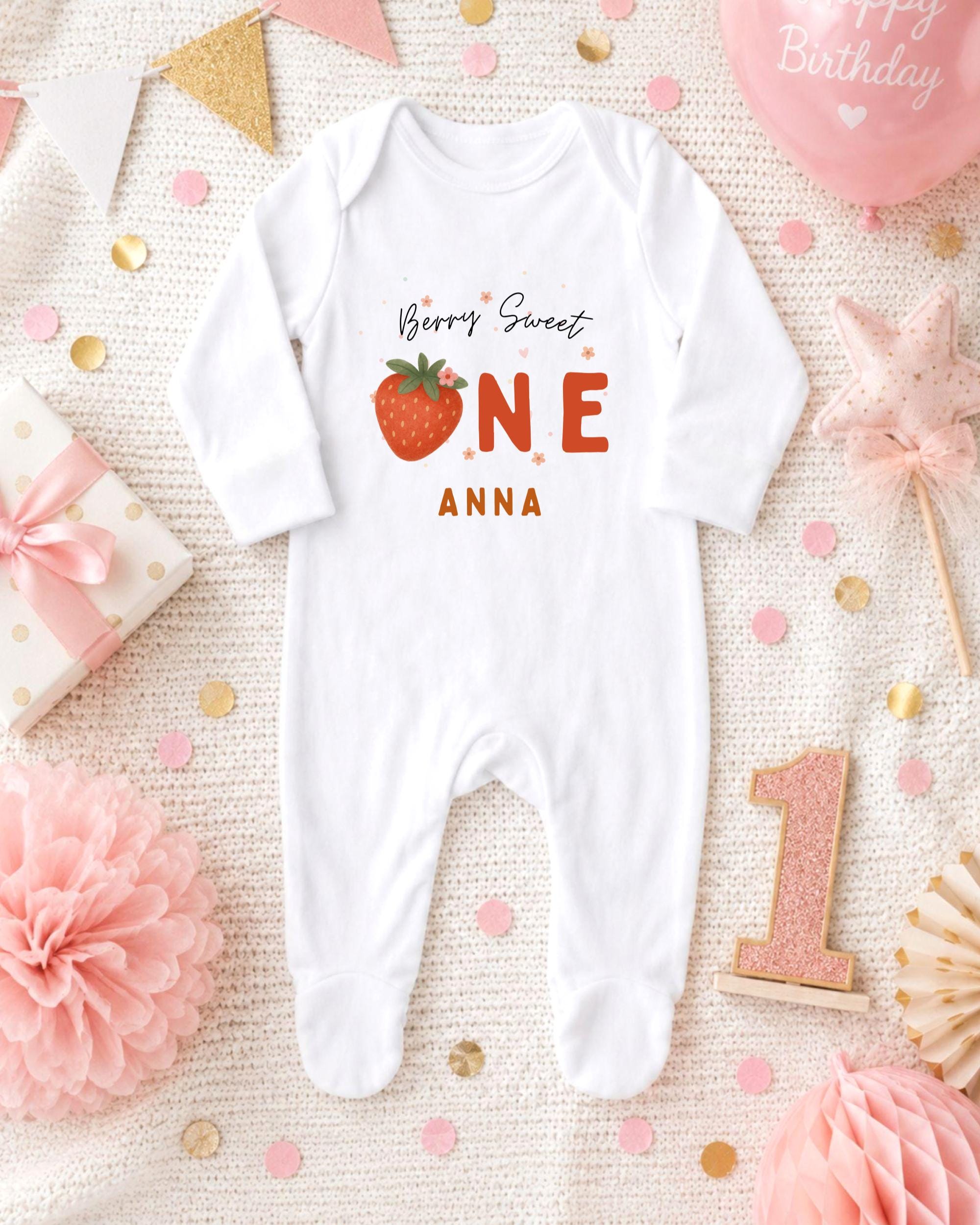 A white onesie with a strawberry design and the text "Berry Sweet Anna" printed on it, surrounded by pink and gold confetti, a pink star, and a pink balloon.