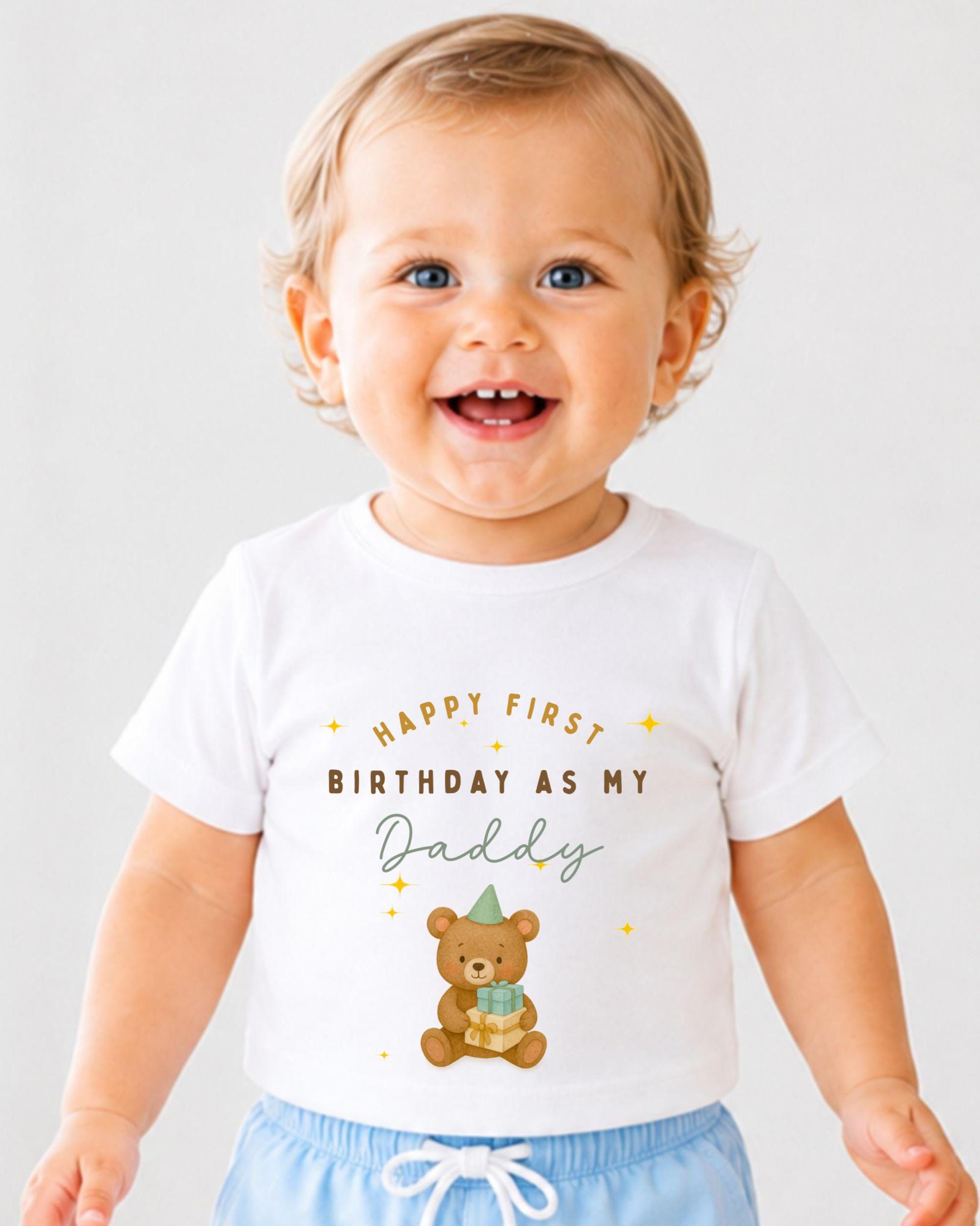 A smiling baby wearing a white t-shirt with a teddy bear and text that says "Happy first birthday as my Daddy".