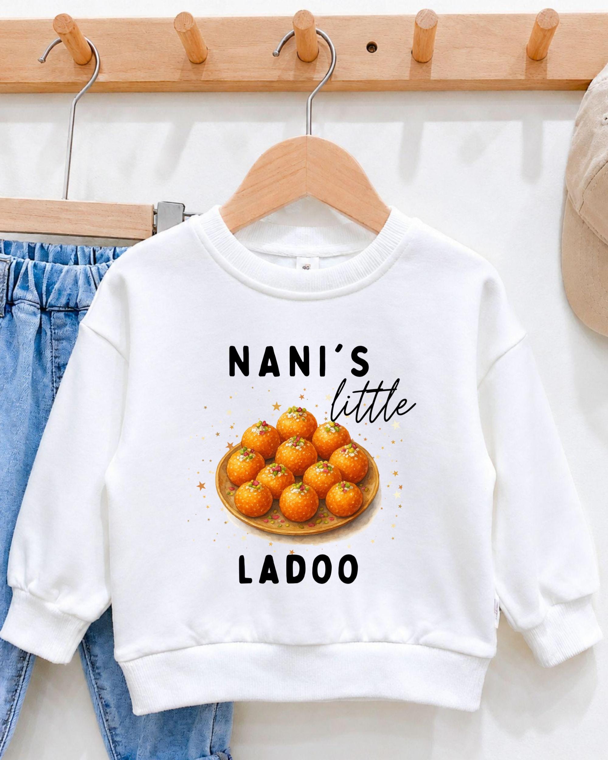 A white sweatshirt with a graphic design featuring a plate of oranges and the text "NANI'S LITTLE LADOO" printed on it.