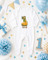 A white onesie with a cartoon image of a giraffe and the name " Josh" printed on it, surrounded by birthday decorations and confetti.