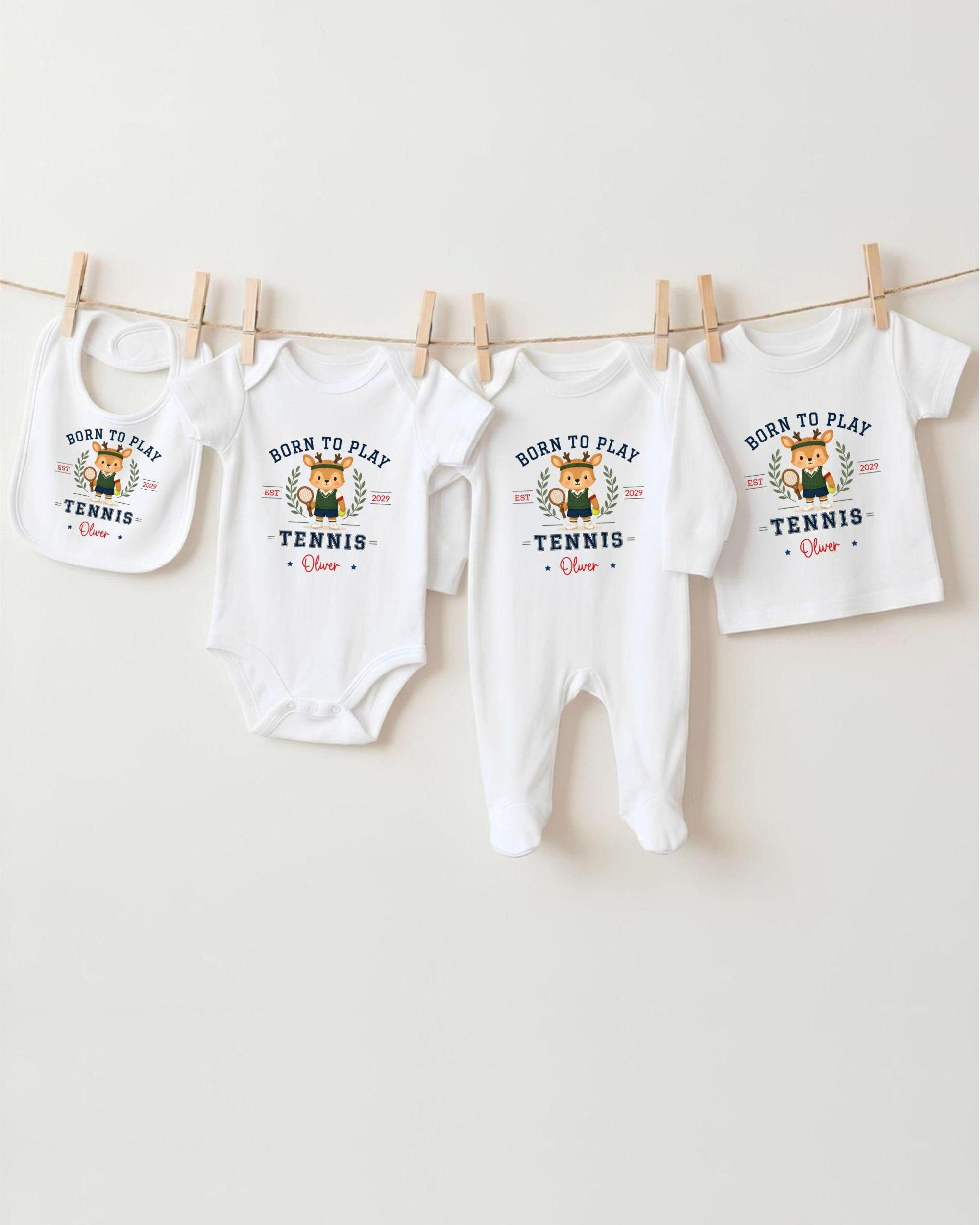 A row of four white baby clothes with the text "Born to play tennis" printed on them, hanging on a clothesline.