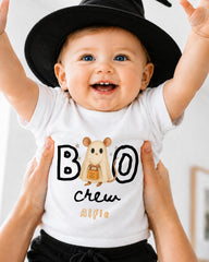 A smiling baby wearing a white t-shirt with a cartoon character and the text "BOO crew Alfie" is being held up by someone's hands.