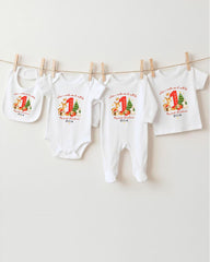 A row of four white baby clothes with personalized Christmas-themed designs hanging on a clothesline.