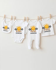 A collection of baby clothes, including onesies and bibs, hanging on a clothesline.