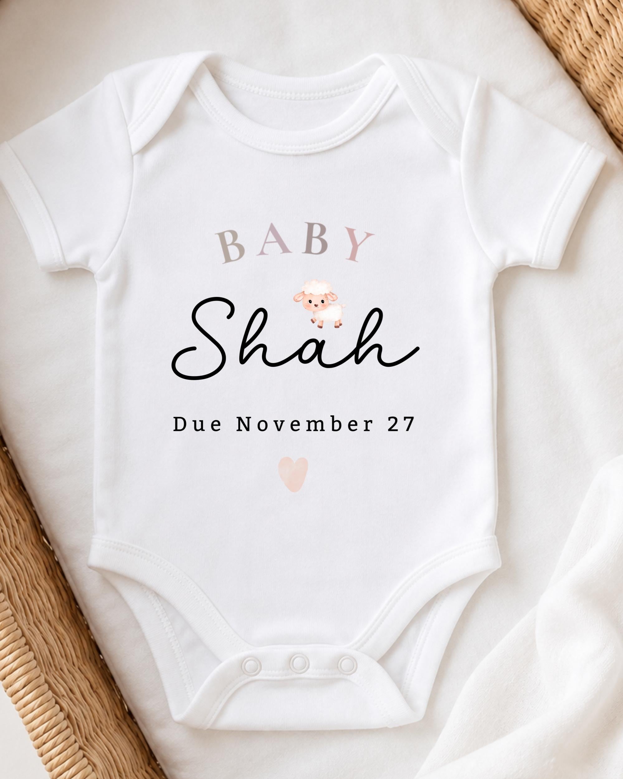 A white baby onesie with the text "BABY Shah Due November 27" printed on it.