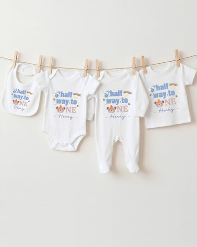 A collection of baby clothes, including onesies and pants, hanging on a clothesline.