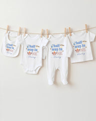 A collection of baby clothes, including onesies and pants, hanging on a clothesline.