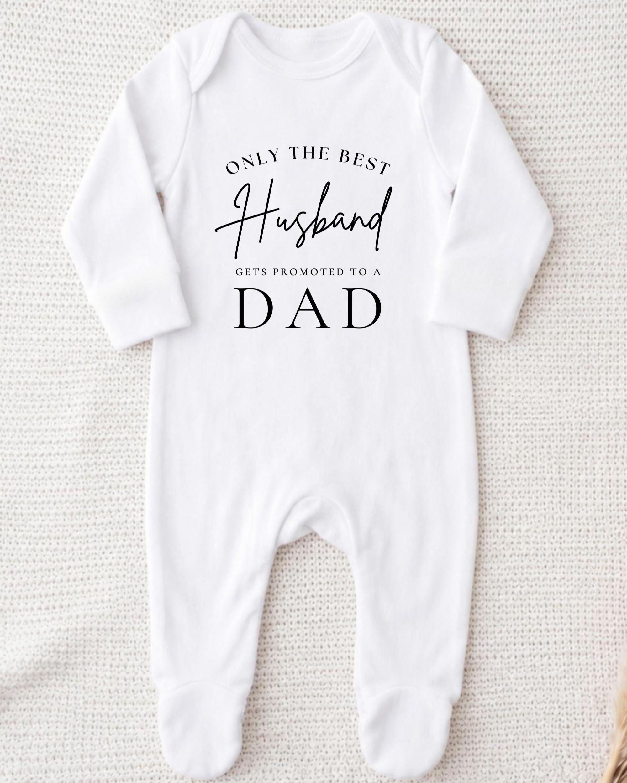A white onesie with the text "Only the best husband gets promoted to a dad" printed on it.