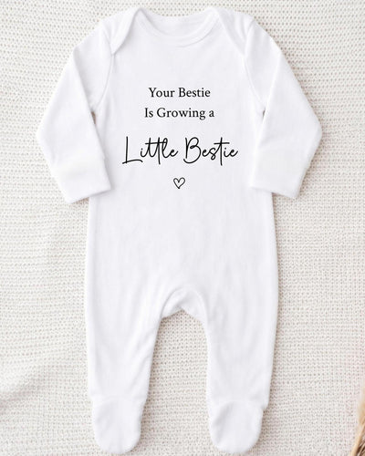 White Bib with black 'Your Bestie Is Growing a Little Bestie' lettering and an outline heart for a bestie pregnancy announcement.