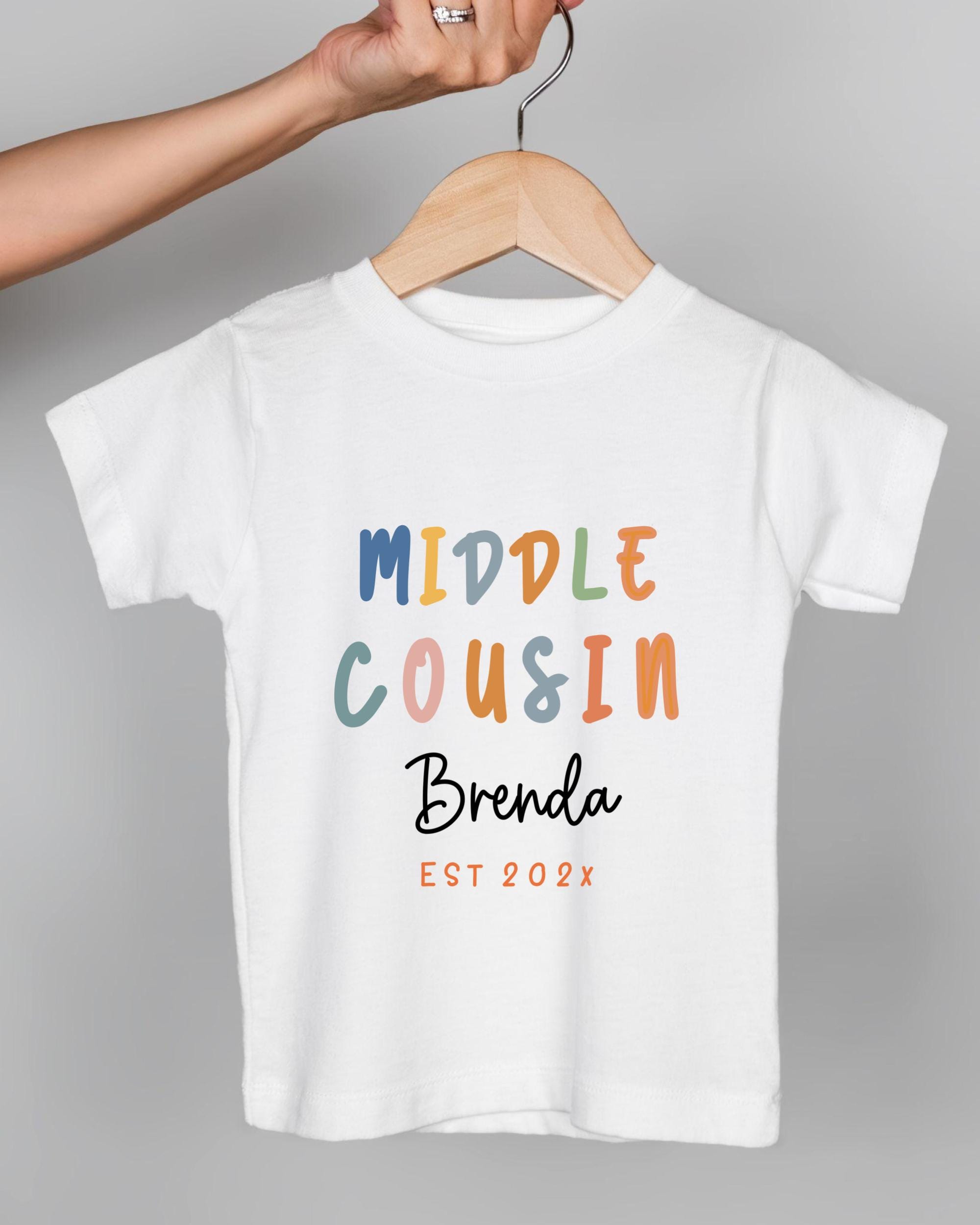 A white t-shirt with text printed on it, hanging on a wooden hanger.
