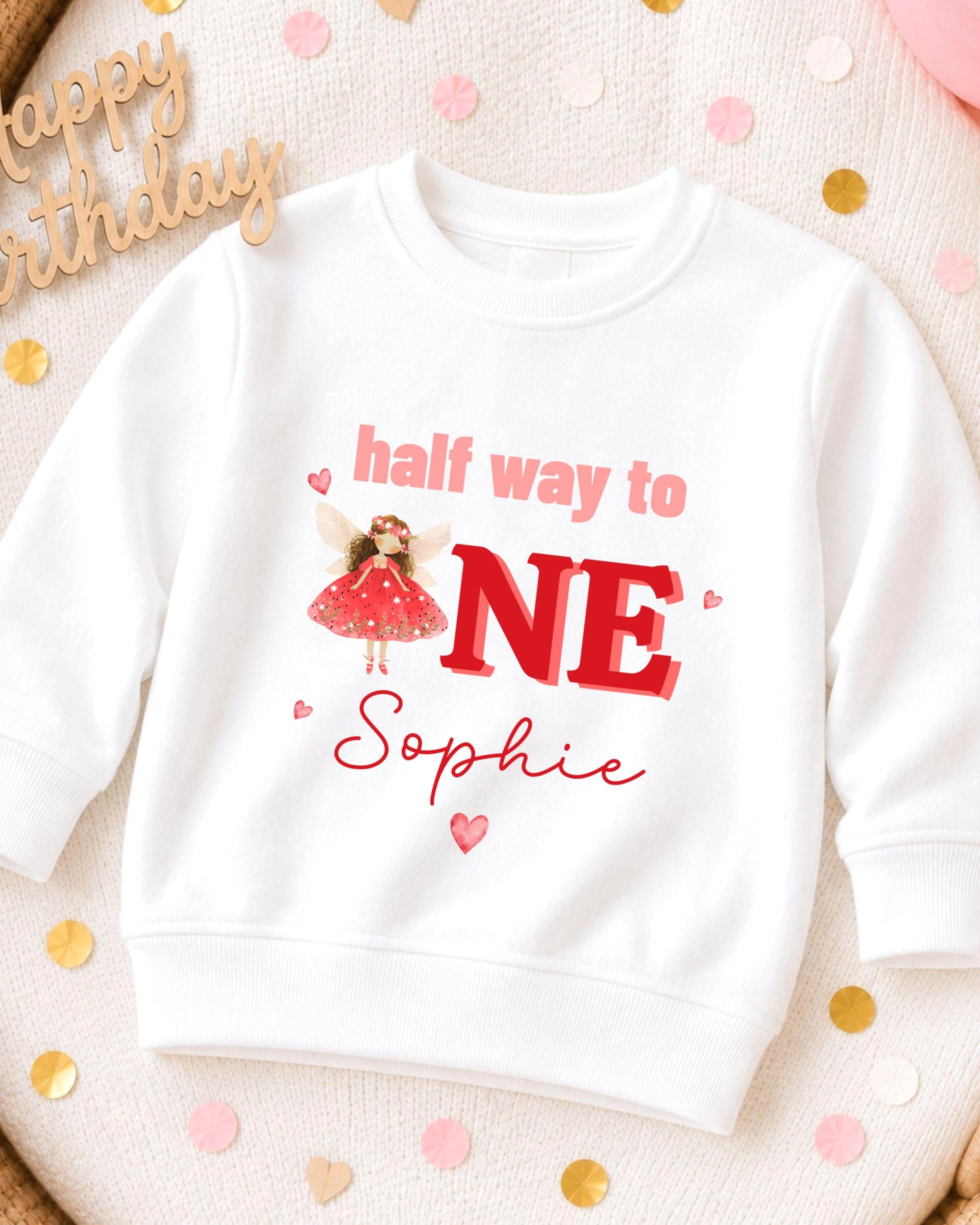 A white sweatshirt with a personalized design on it, featuring a fairy character and the text "half way to one Sophie".