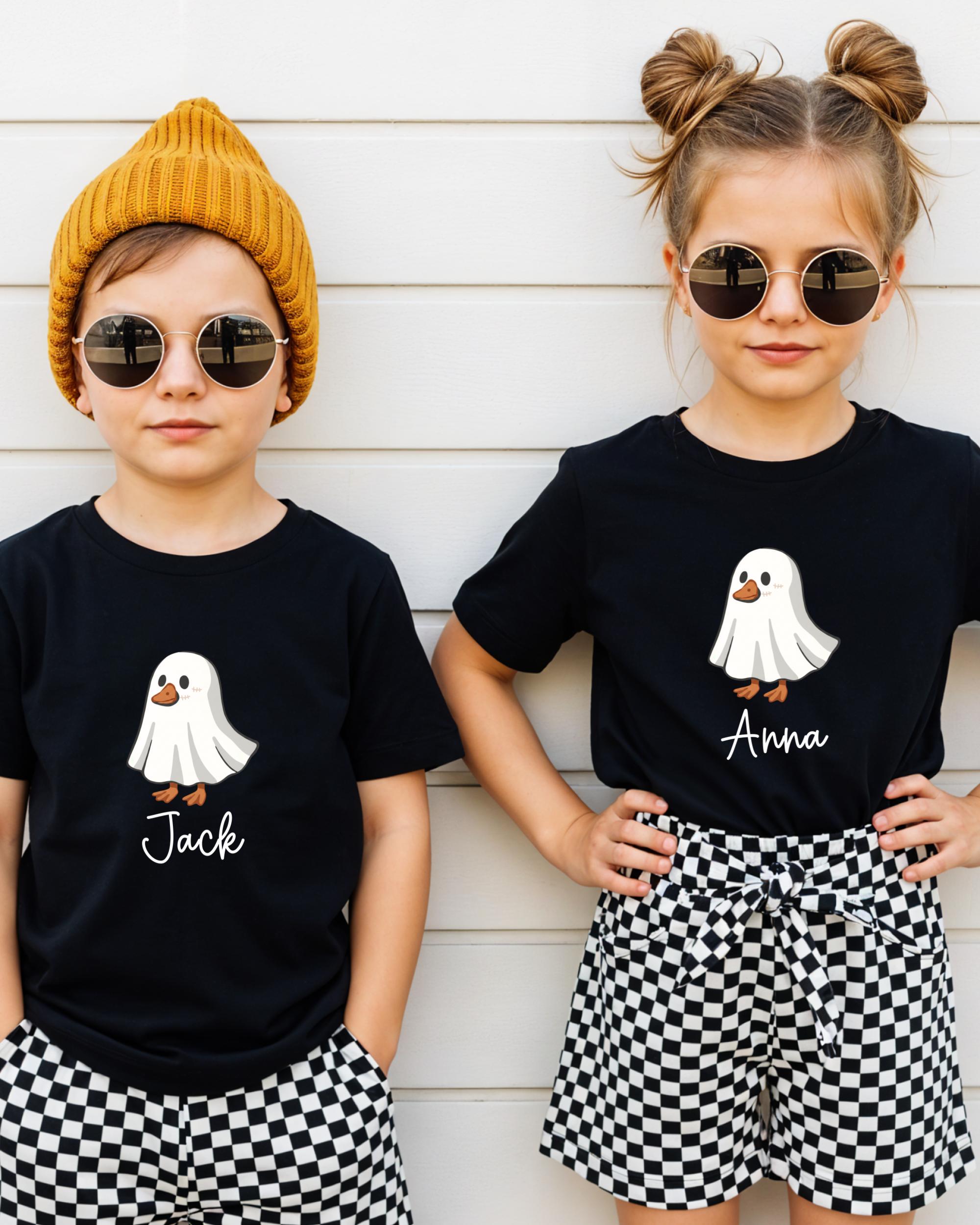 Two children wearing black t-shirts with a ghost graphic and the name "Jack" printed on them, along with round sunglasses and a yellow beanie.