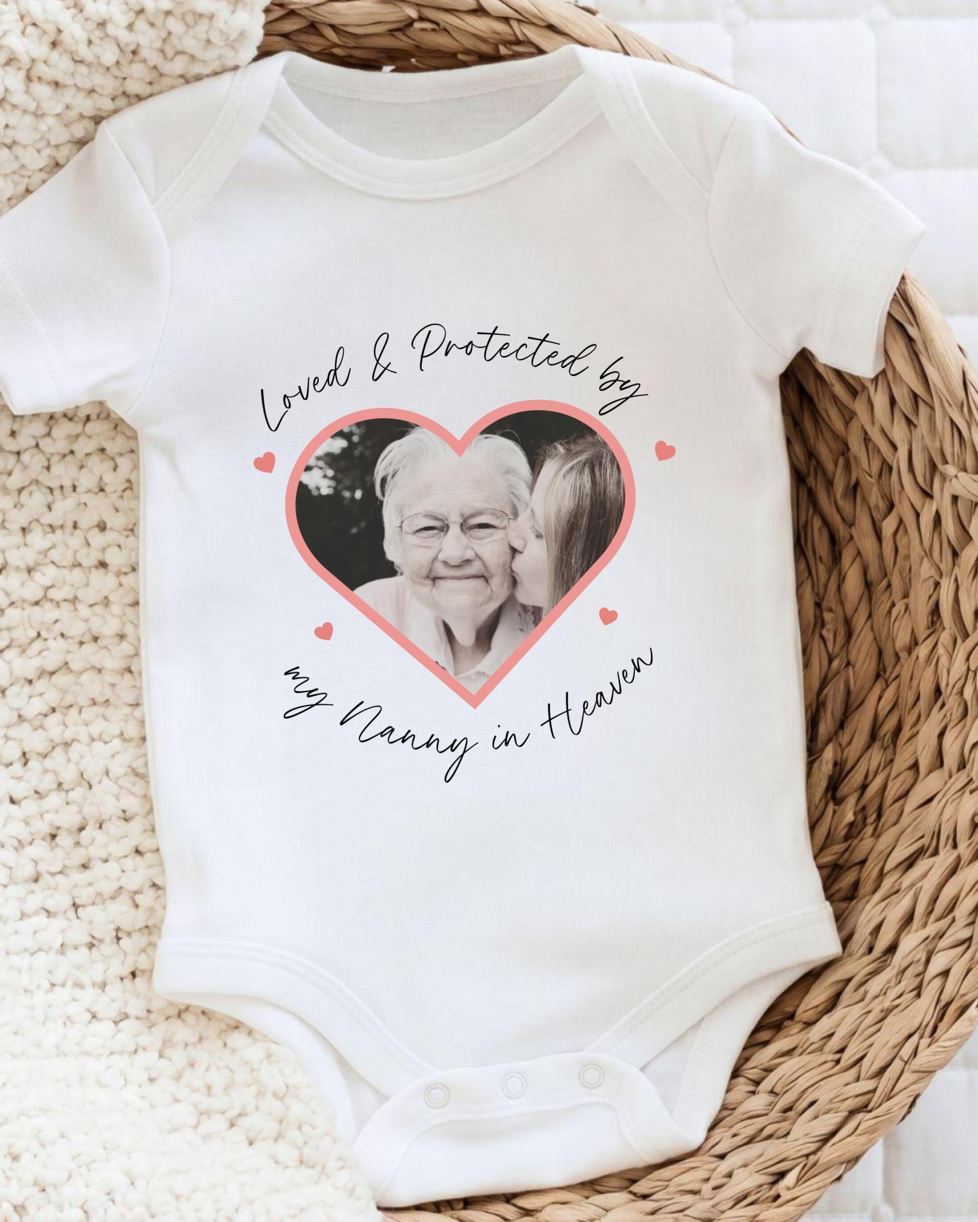 A white baby onesie with a heart-shaped graphic and text printed on it.