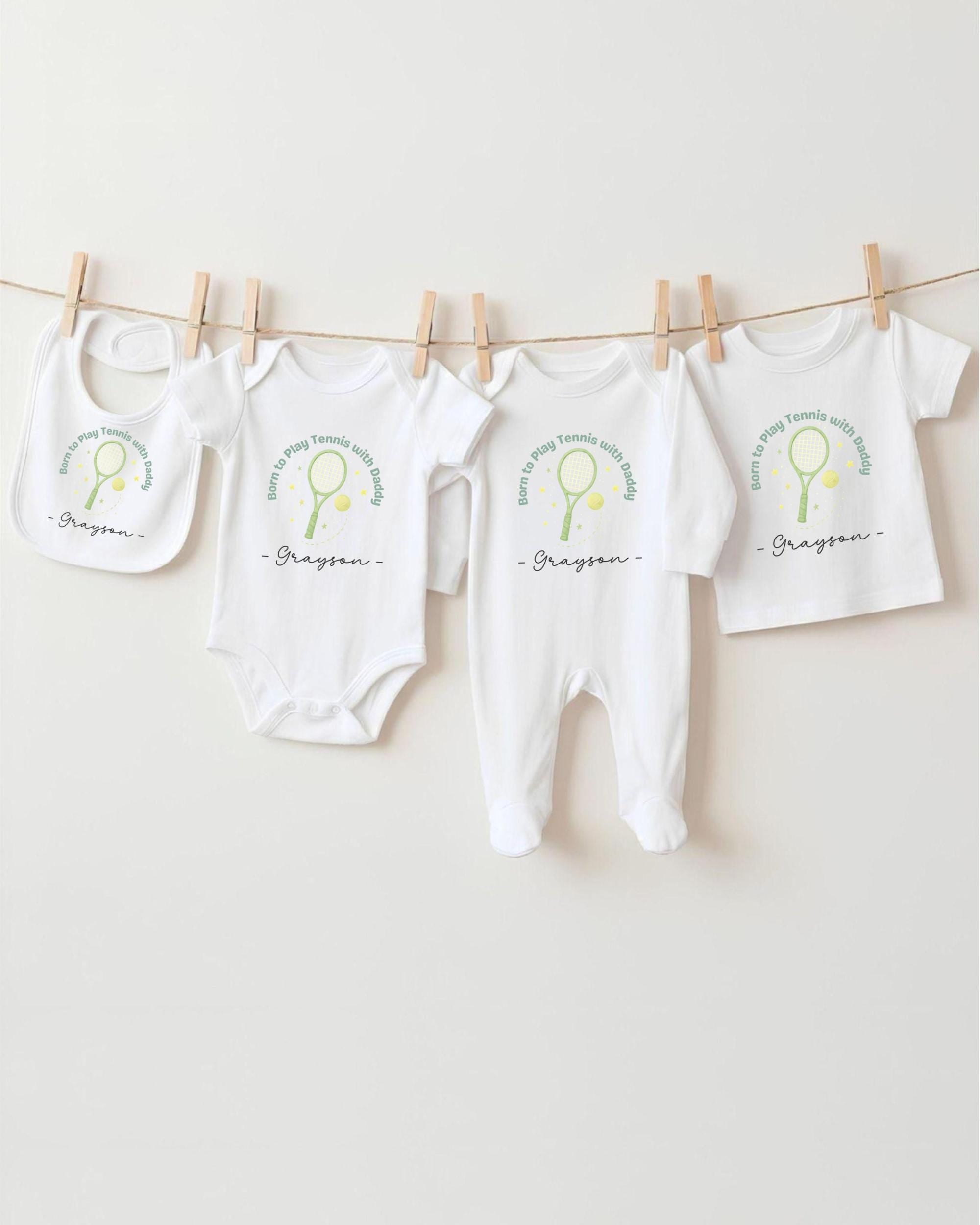 A row of white baby clothes with tennis racket designs hanging on a clothesline.