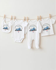 A collection of baby clothes, including onesies and bibs, hanging on a clothesline.