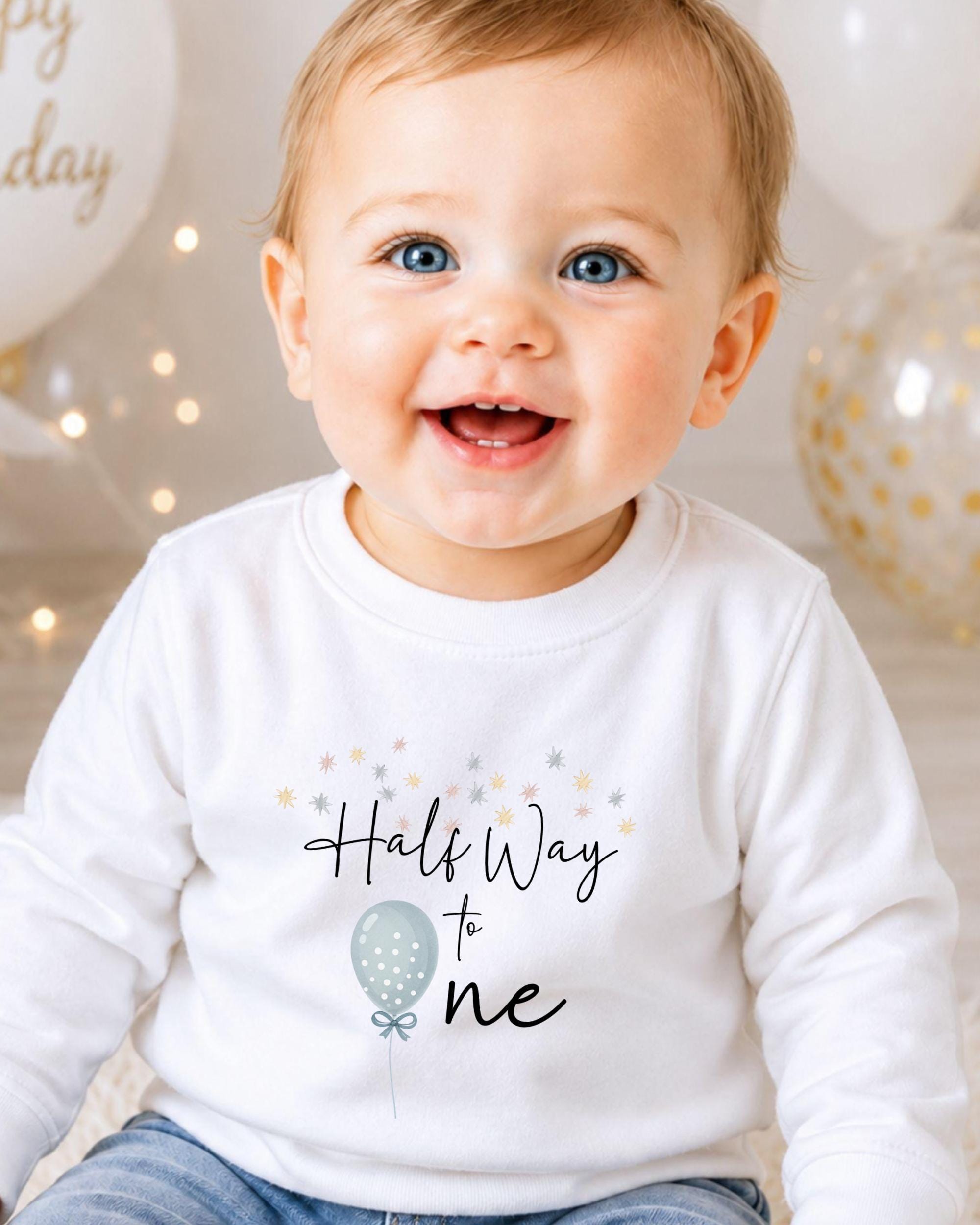 A smiling baby wearing a white shirt with the text "Half Way to One" printed on it.