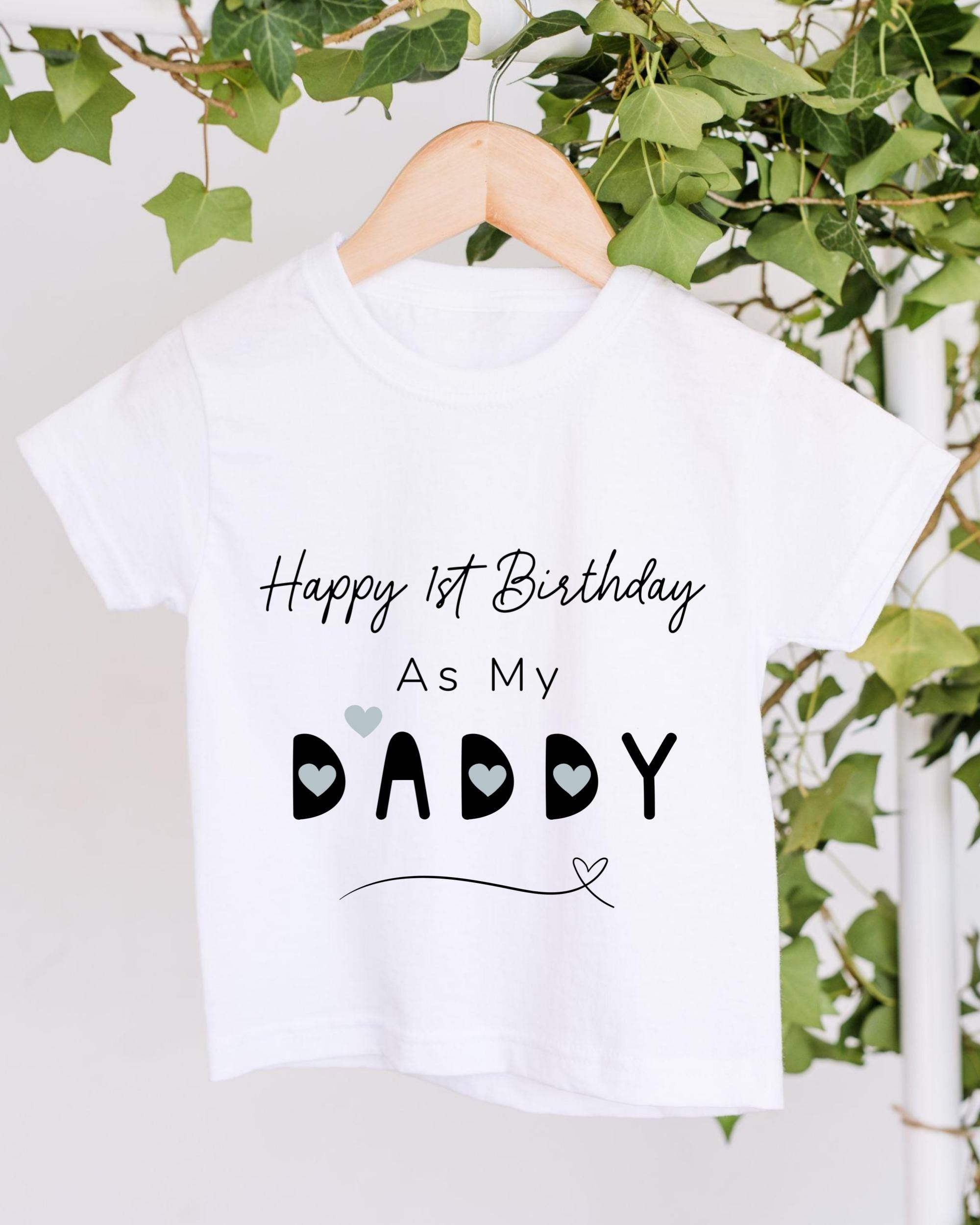 A white t-shirt with a birthday message printed on it, hanging on a wooden hanger.