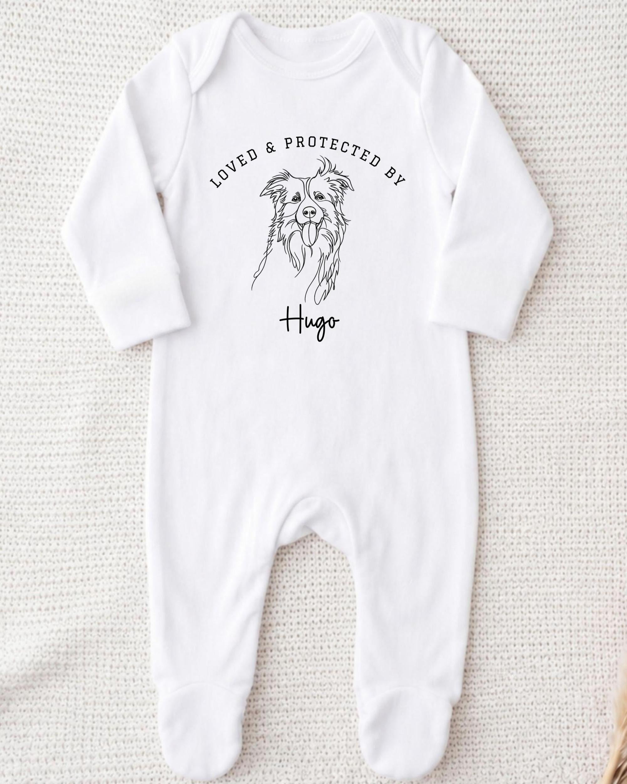 A white onesie with a black illustration of a dog and the text "LOVED & PROTECTED BY Hugo" printed on it.