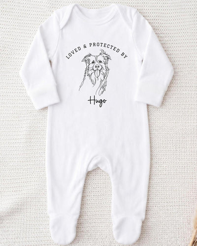 A white bodysuit with a black illustration of a dog and the text "LOVED & PROTECTED BY Hugo" printed on it.