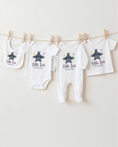 A collection of baby clothes, including bodysuits and bibs, hanging on a clothesline.