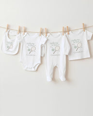 A row of white baby clothes, including onesies and bibs, hanging on a clothesline.
